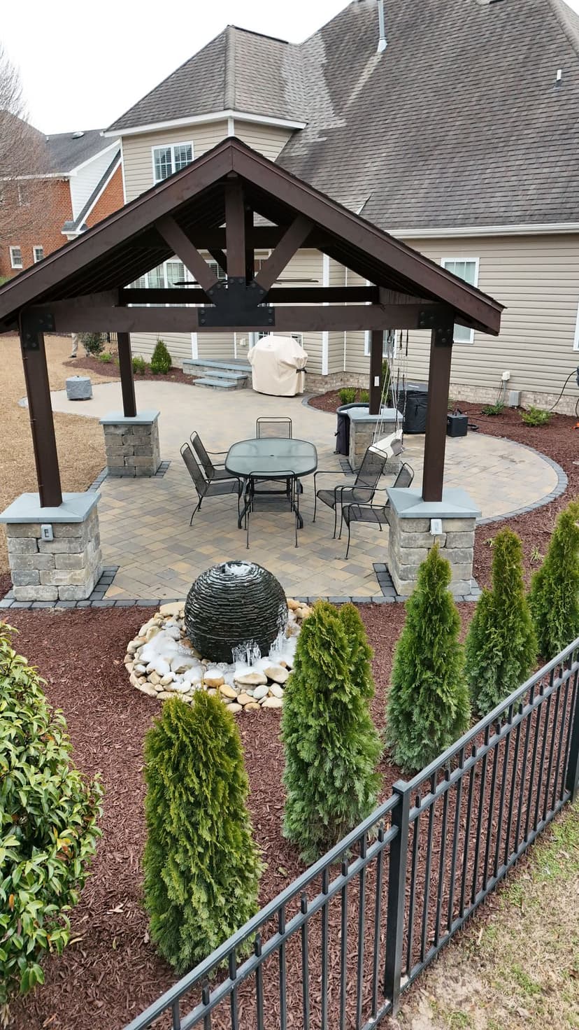 Outdoor patio with a gazebo, seating area, and decorative stone features.